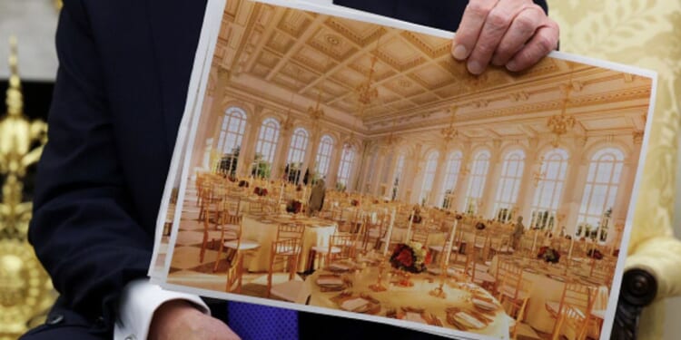 President Trump sits in the Oval Office and shows plans for the White House ballroom on October 22, 2025.
