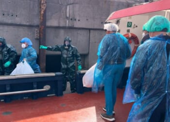 Passengers dressed in masks, plastic suits, and head coverings are escorted off the hantavirus-stricken cruise ship MV Hondius Sunday at the port of Granadilla in Tenerife, Canary Islands, Spain.