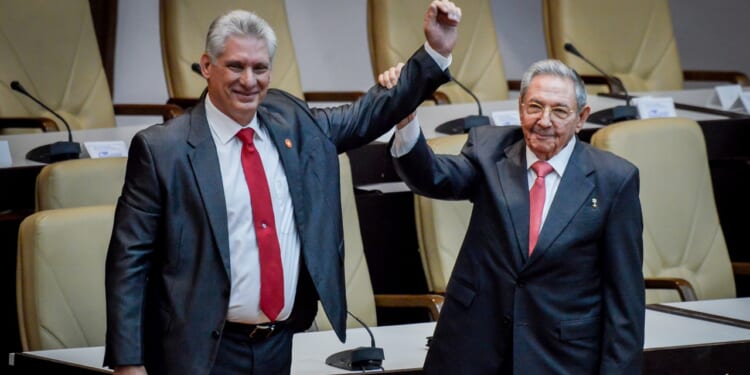 Former Cuban President Raul Castro raises the hand of current President Miguel Diaz-Canel