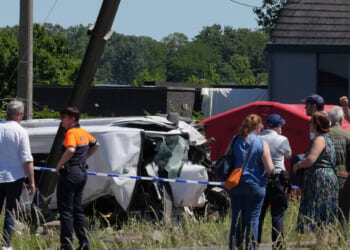 Police and residents gather around a level crossing where a train collided with a van in Buggenhout, Belgium, on May 26, 2026.