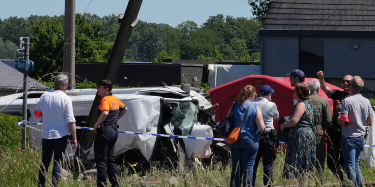 Police and residents gather around a level crossing where a train collided with a van in Buggenhout, Belgium, on May 26, 2026.