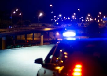 Cop lights flash as they park on a roadway.