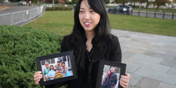 Grace Jin Drexel, the daughter of detained Chinese pastor Jin Mingri, holds up framed photos of Mingri and his family in Washington, DC on Oct. 30, 2025.