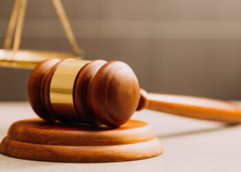 A gavel lays near a balancing scale.