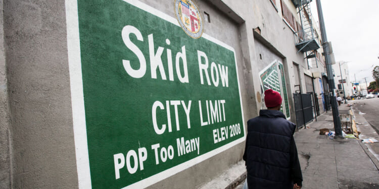 Green sign with white lettering reading "Skid Row City Limit. Pop Too Many."