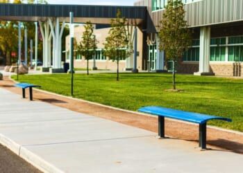 A high school with a bus stop and benches in the United States.