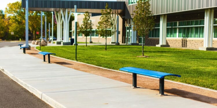 A high school with a bus stop and benches in the United States.