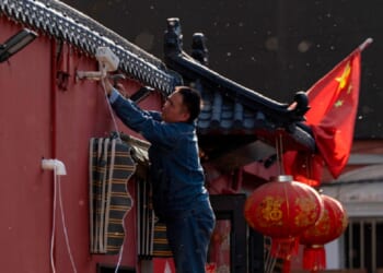 A man sets up a surveillance camera outside a restaurant with a Chinese national flag in Beijing on Friday as the capital city prepared for President Donald Trump's arrival.