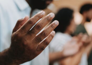 Man and group of fellow Christians gather in a line of prayer.