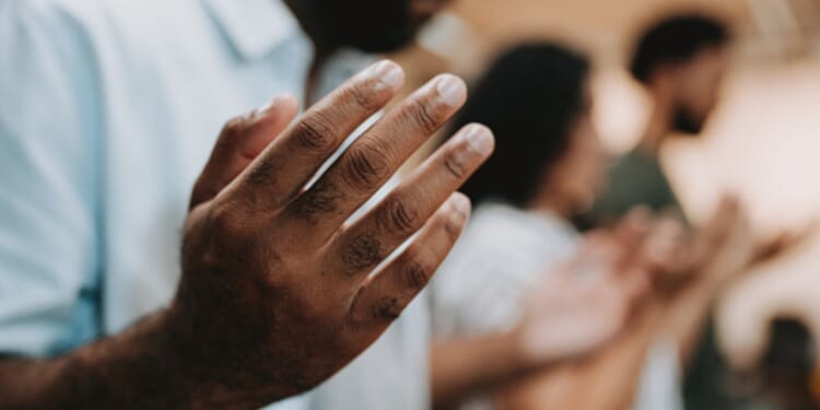 Man and group of fellow Christians gather in a line of prayer.