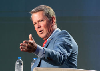 Georgia Gov. Brian Kemp gestures while speaking at a podium.