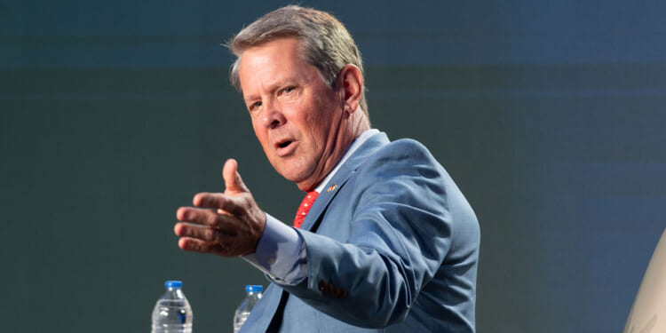 Georgia Gov. Brian Kemp gestures while speaking at a podium.