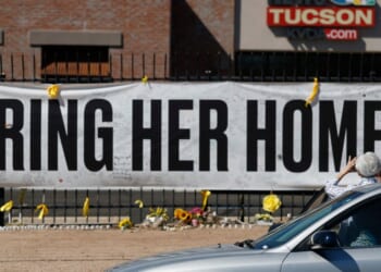 A person takes a photo of a Nancy Guthrie memorial on March 3 in front of the KVOA-TV station in Tucson, Arizona.
