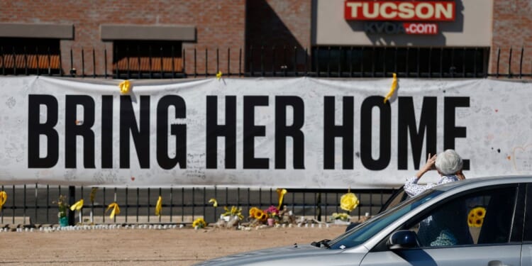 A person takes a photo of a Nancy Guthrie memorial on March 3 in front of the KVOA-TV station in Tucson, Arizona.