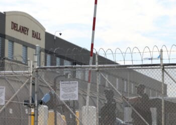 Immigration and Customs Enforcement agents stand guard behind the gate as protestors gather at Delaney Hall, which is being used as an Immigration and Customs Enforcement detention center in Newark, New Jersey, on May 26, 2026.