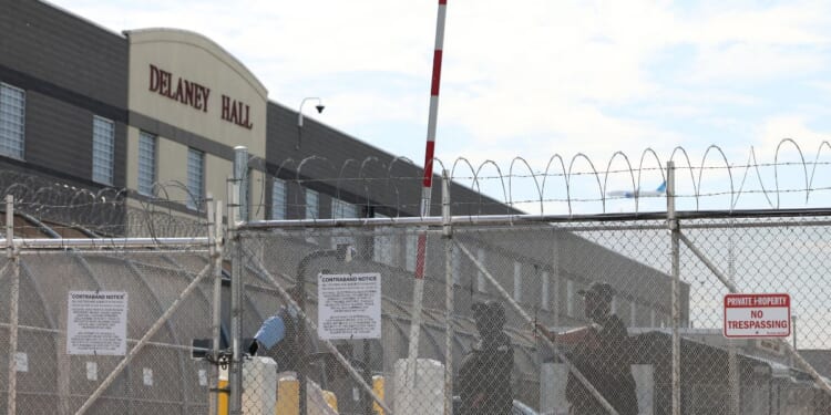 Immigration and Customs Enforcement agents stand guard behind the gate as protestors gather at Delaney Hall, which is being used as an Immigration and Customs Enforcement detention center in Newark, New Jersey, on May 26, 2026.