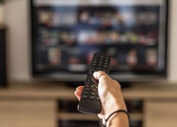 A person turns on a television with a remote control.