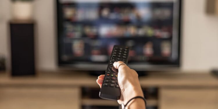 A person turns on a television with a remote control.