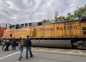 Pedestrians approach a Union Pacific freight train traveling past Jack London Square, Oakland, California, on April 26, 2026.