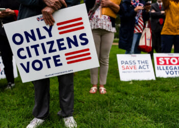Attendees hold 'Only Citizens Vote' signs at a rally.