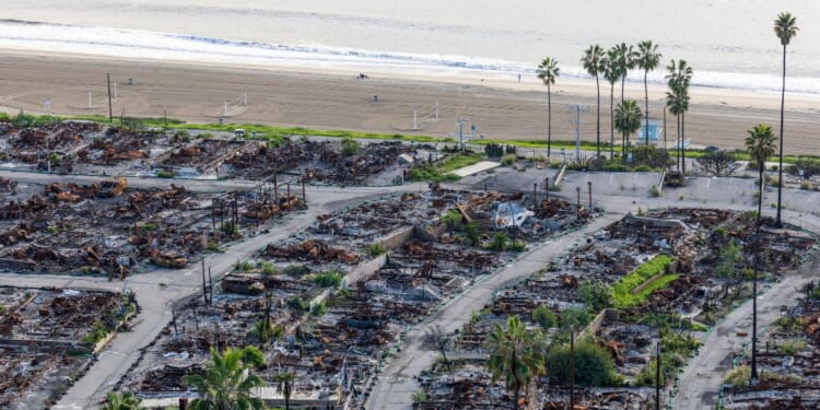 An American flag and sand bag stands on a cliff overlooking the remains of the Pacific Palisades Bowl Mobile Estates, which was destroyed in the 2025 Palisades fire, on the one year anniversary in Pacific Palisades on Jan. 6, 2026.