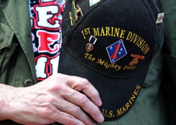 A veteran marine holds his commemorative hat on top of his heart.