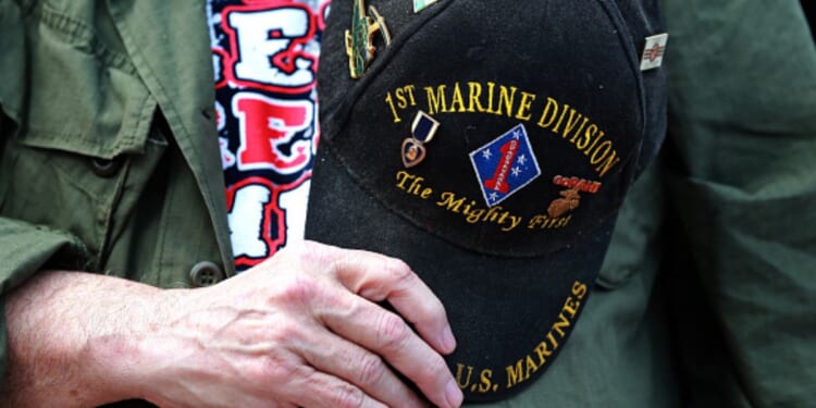 A veteran marine holds his commemorative hat on top of his heart.