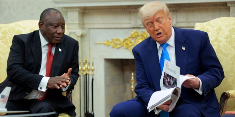 President of South Africa Cyril Ramaphosa looks on as President Donald Trump displays articles he says report violence against white South Africans in the Oval Office of the White House on May 21, 2025, in Washington, D.C.