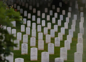 Headstones are seen through a foggy window ahead of members of the 3rd U.S. Infantry Regiment placing flags in front of each headstone at Arlington National Cemetery on May 21, 2026 in Arlington, Virginia. Before dawn soldiers begin the process of placing a flag in front of approximately 260,000 headstones ahead of Memorial Day. (Photo by Heather Diehl/Getty Images)