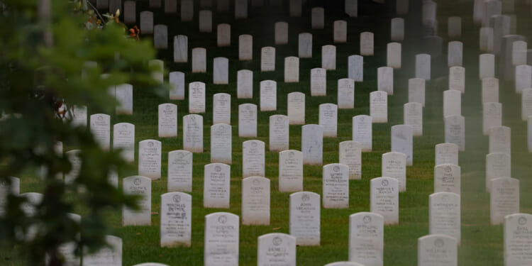 Headstones are seen through a foggy window ahead of members of the 3rd U.S. Infantry Regiment placing flags in front of each headstone at Arlington National Cemetery on May 21, 2026 in Arlington, Virginia. Before dawn soldiers begin the process of placing a flag in front of approximately 260,000 headstones ahead of Memorial Day. (Photo by Heather Diehl/Getty Images)