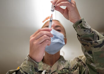 A Preventative Medicine Services technician fills a syringe with a Janssen COVID-19 vaccine.
