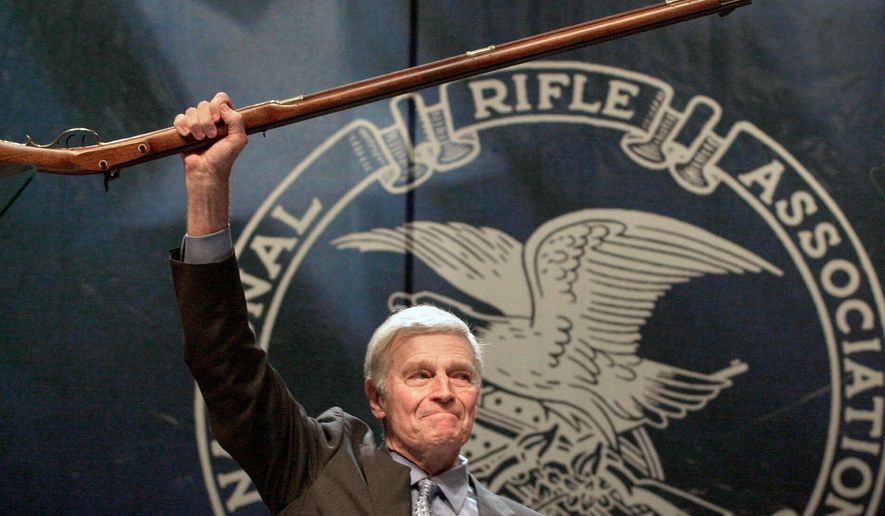 FILE - NRA president Charlton Heston holds up a musket as he tells the members attending the 129th Annual Meeting & Exhibit in Charlotte, N.C., that they can have his gun when they pry it, "from my cold dead hands," drawing a standing ovation, May 20, 2000. (AP Photo/Ric Feld, File)