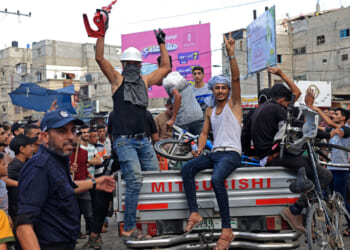 A group of Palestinians on the back of a pickup truck celebrate after returning from Oct. 7 massacre.