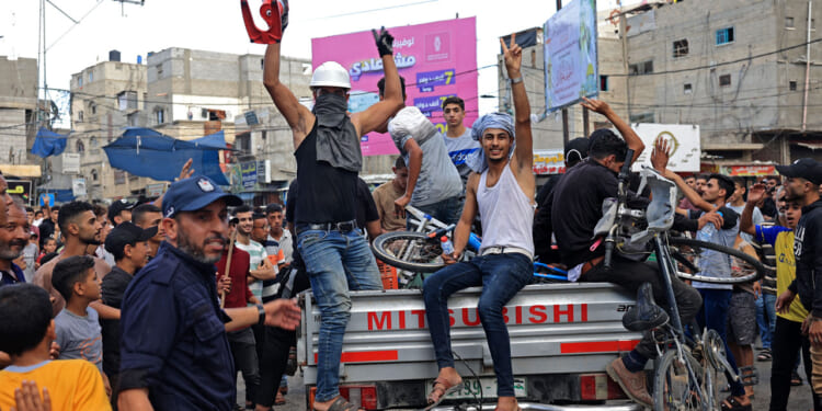 A group of Palestinians on the back of a pickup truck celebrate after returning from Oct. 7 massacre.