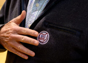 A man places his hand by the "Ohio Voted" sticker on his suit jacket.