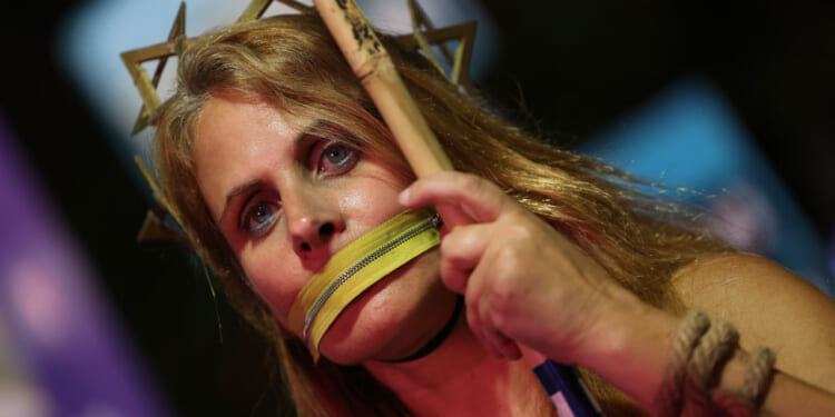 A woman stands with a symbolic zipper around her mouth during a demonstration at Hostage Square in Tel Aviv on October 25, 2025, as people call for the release of all the bodies of hostages held in Gaza by the Palestinian militant group Hamas.