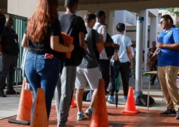 A Broward County gate supervisor examines students as they enter the campus for weapons on June 24, 2024.