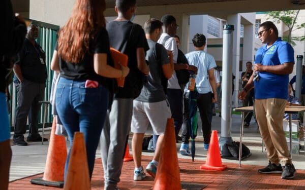 A Broward County gate supervisor examines students as they enter the campus for weapons on June 24, 2024.