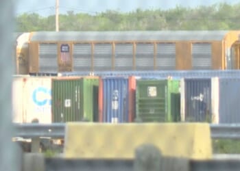 Union Pacific train cars can be spotted through a gate stationed at the rail yard in Laredo, Texas.