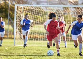 A girl's soccer team practices on a sunny day.