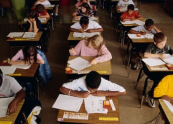 Students sit in a classroom and complete schoolwork.
