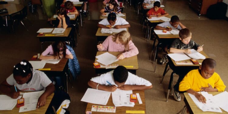 Students sit in a classroom and complete schoolwork.