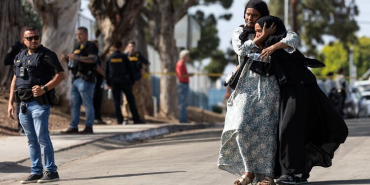 Two women react as they leave a reunification center following the shooting at the Islamic Center of San Diego in southern California Monday.
