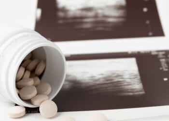 Abortion pills are depicted in front of an ultrasound.