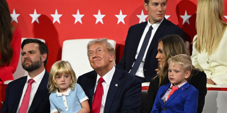 Donald Trump with granddaughter in his lap, grandson at his side, daughter and son-in-law behind him, and JD Vance to his right.
