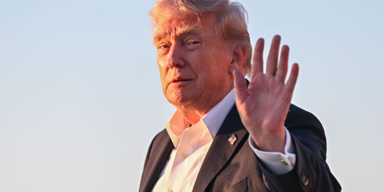 President Donald Trump waves to the press.