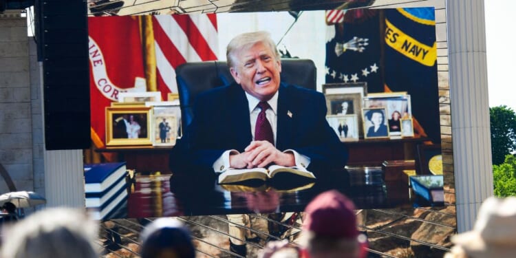 Attendees watch a pre-recorded video of President Donald Trump reading from the Bible during "Rededicate 250: A National Jubilee of Prayer, Praise, and Thanksgiving" on the National Mall in Washington, D.C., on May 17, 2026.