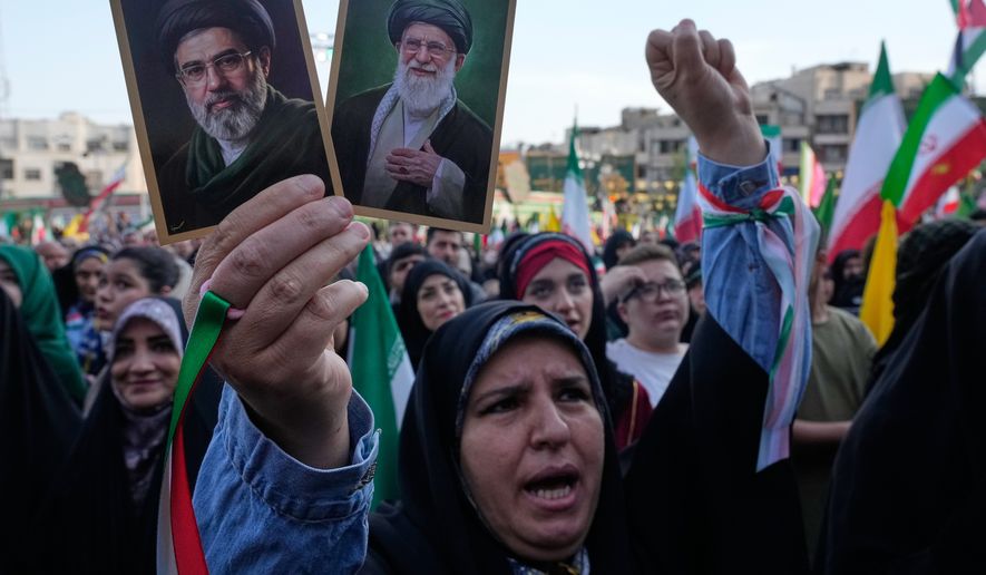 A woman holds up pictures of the Iranian Supreme Leader Ayatollah Mojtaba Khamenei, left, and his father, the slain Ayatollah Ali Khamenei, during a state-organized rally in Tehran, Iran, April 29, 2026. (AP Photo/Vahid Salemi, File)