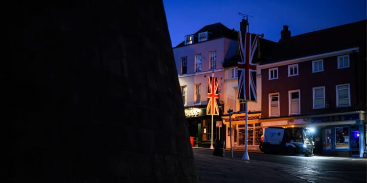 United Kingdom banners are illuminated by a headlight in the street outside Windsor Castle on Sept. 12, 2025, in Windsor, England.