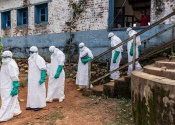 Health workers wearing protective equipment walk outside the General Referral Hospital during the Ebola outbreak response on May 21, 2026, in Mongbwalu, Democratic Republic of Congo.